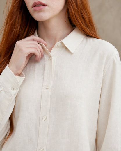 Close-up van de getailleerde kraag en knopenlijst van een roomwit linnen blouse.