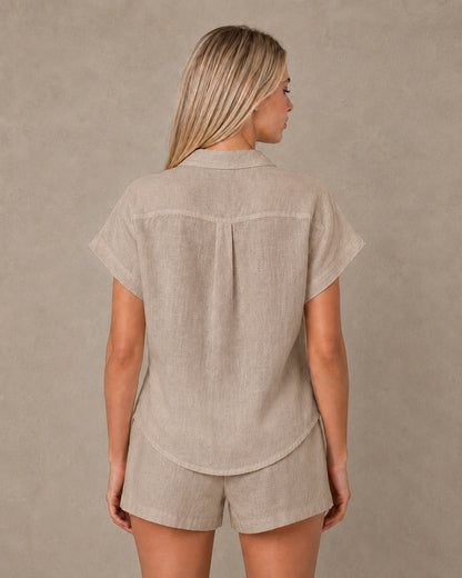 Achteraanzicht van een slank gesneden taupe linnen blouse met korte mouwen.