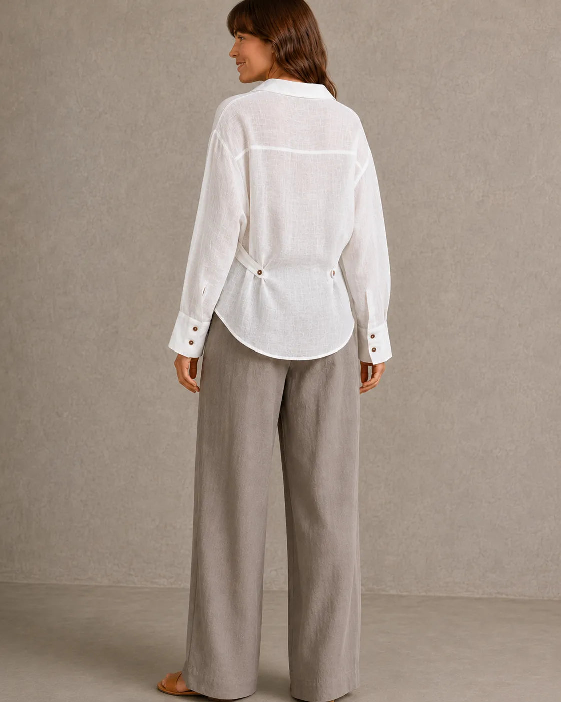 Achteraanzicht van een wit linnen blouse met lange mouwen en getailleerde taille.
