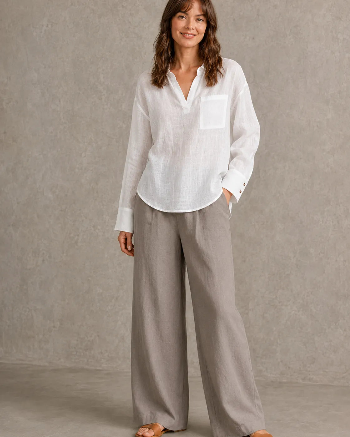 Volledige look van een vrouw in een wit linnen blouse met getailleerde taille, gecombineerd met een wijde broek.