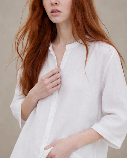 Close-up van het kleine open kraagje en de V-hals van een wit linnen blouse.