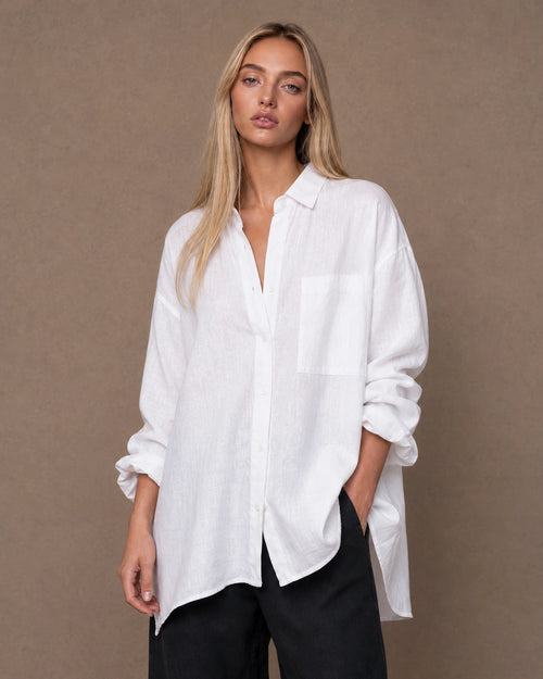 Vrouw draagt een relaxte wit linnen blouse met reverskraag en lange mouwen, vooraanzicht.