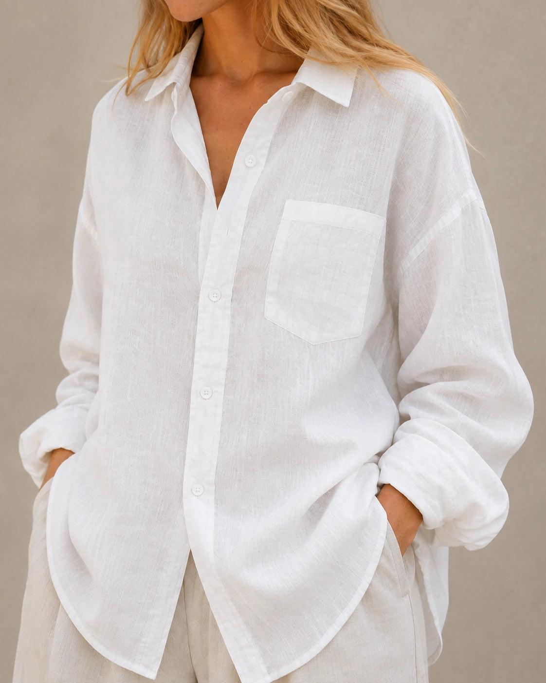 Close-up van de open kraag en halslijn van een oversized wolkenwit linnen blouse.
