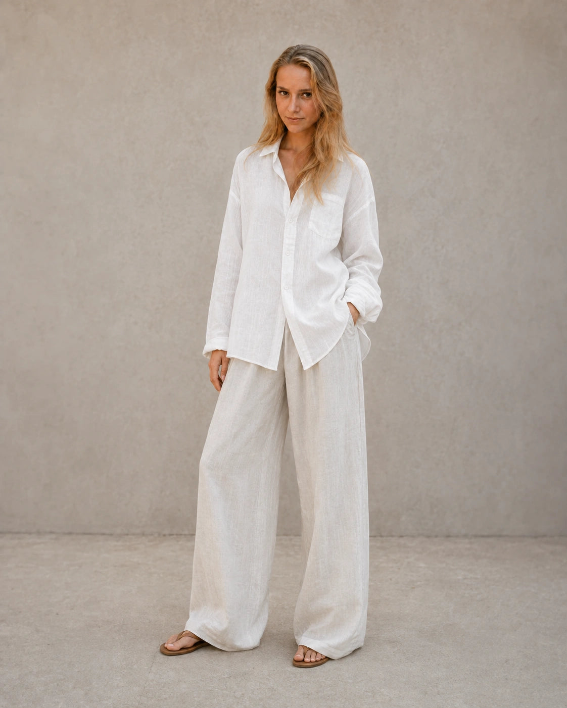 Volledige look van een vrouw in een oversized wolkenwit linnen blouse, gecombineerd met een wijde broek.