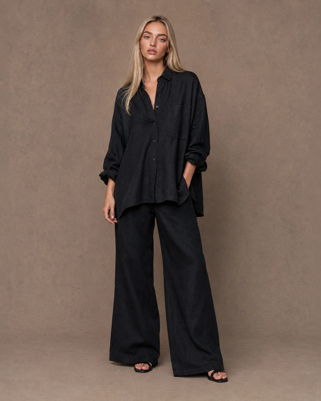 Volledige look van een vrouw in een relaxte zwart linnen blouse, gecombineerd met een wijde broek.