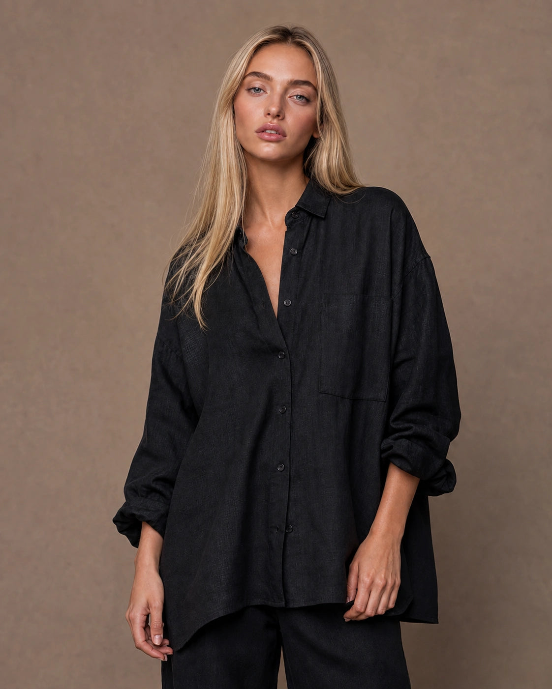 Vrouw draagt een relaxte zwart linnen blouse met reverskraag en lange mouwen, vooraanzicht.