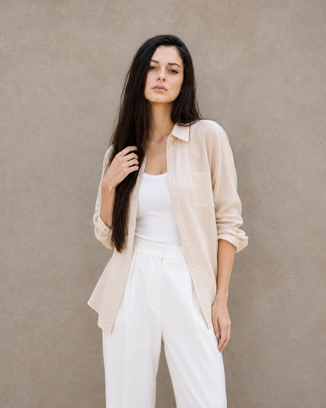 Woman wearing an open, cardigan-style beige lyocell-linen shirt with a patch pocket, over a white top.