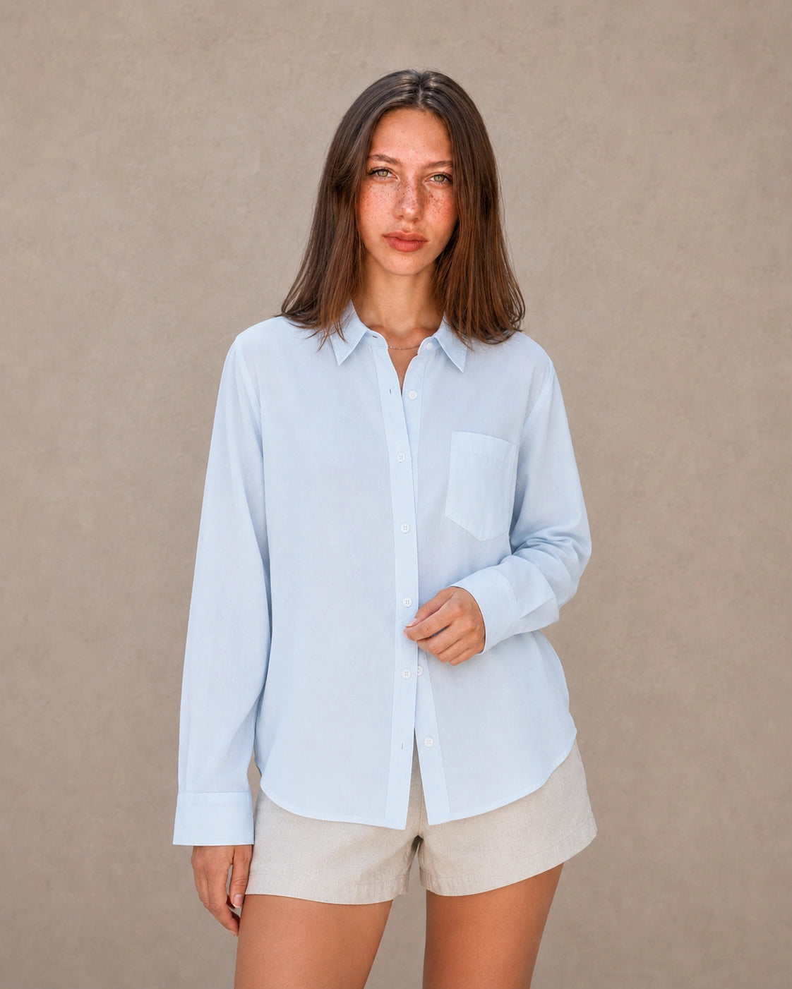 Vrouw draagt een blauw tencel-linnen doorknoopblouse met reverskraag, vooraanzicht.