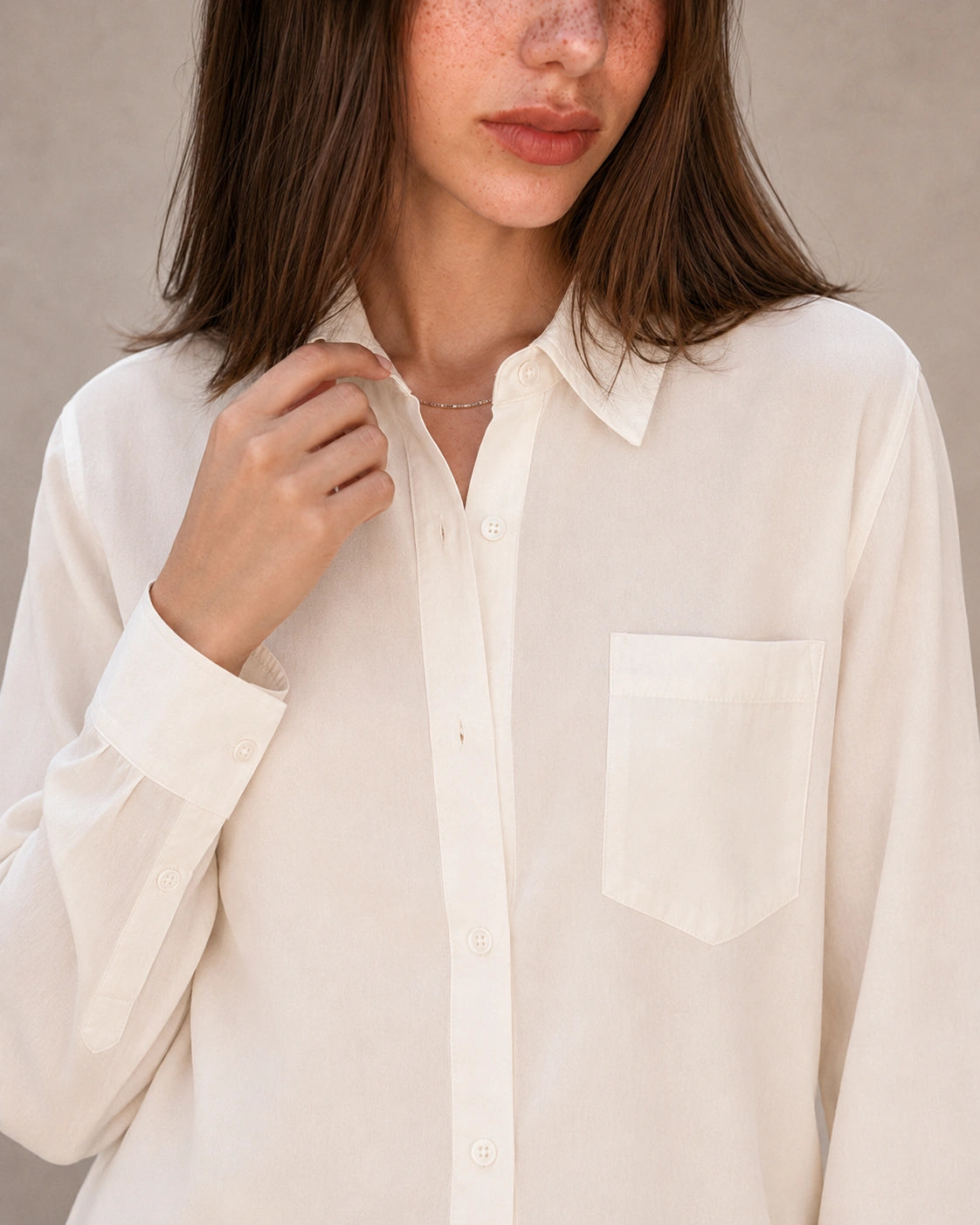 Close-up van de kraag en knopenlijst van een gebroken wit tencel-linnen blouse.