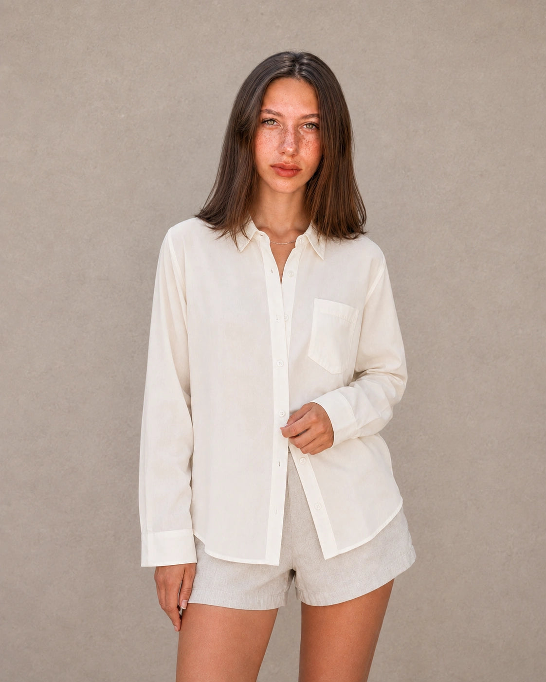 Vrouw draagt een gebroken wit tencel-linnen doorknoopblouse met reverskraag, vooraanzicht.