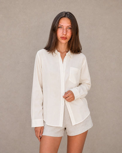 Vrouw draagt een gebroken wit tencel-linnen doorknoopblouse met reverskraag, vooraanzicht.