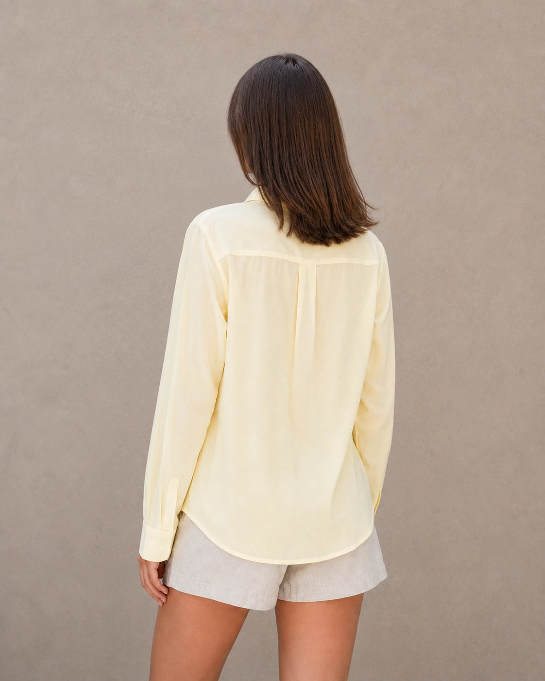 Achteraanzicht van een geel tencel-linnen doorknoopblouse met lange mouwen.