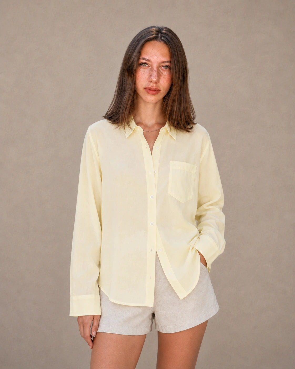 Vrouw draagt een geel tencel-linnen doorknoopblouse met reverskraag, vooraanzicht.