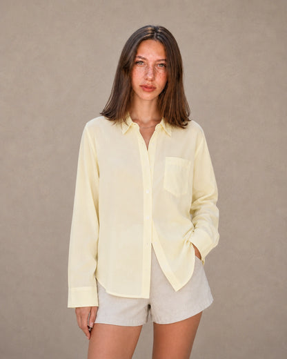 Vrouw draagt een geel tencel-linnen doorknoopblouse met reverskraag, vooraanzicht.