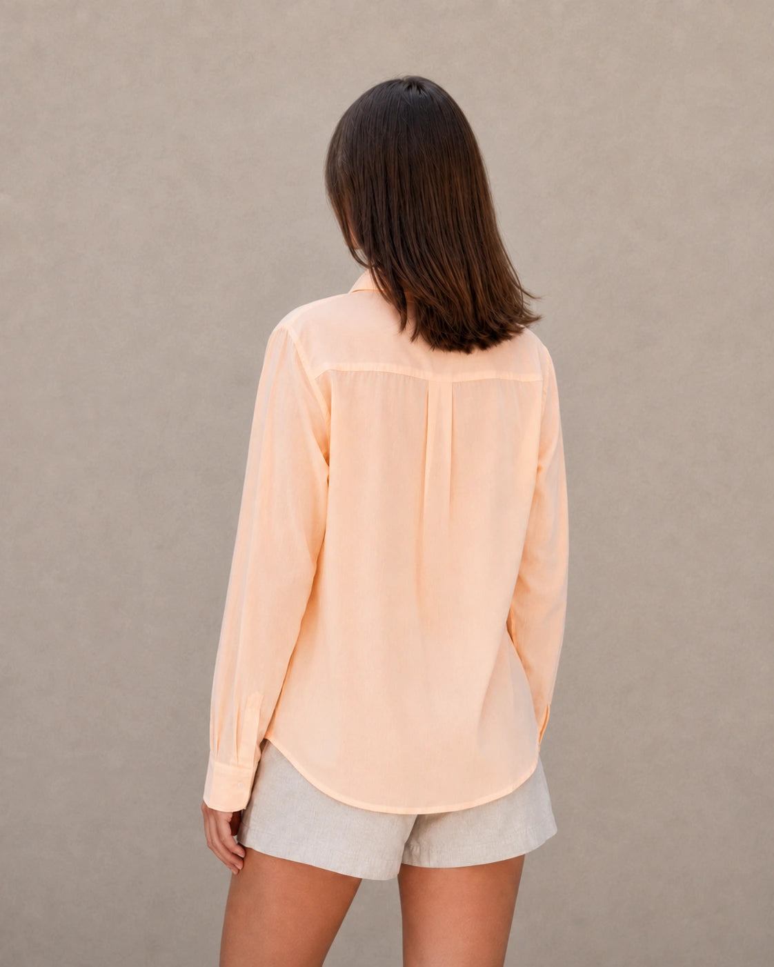 Achteraanzicht van een oranje tencel-linnen doorknoopblouse met lange mouwen.