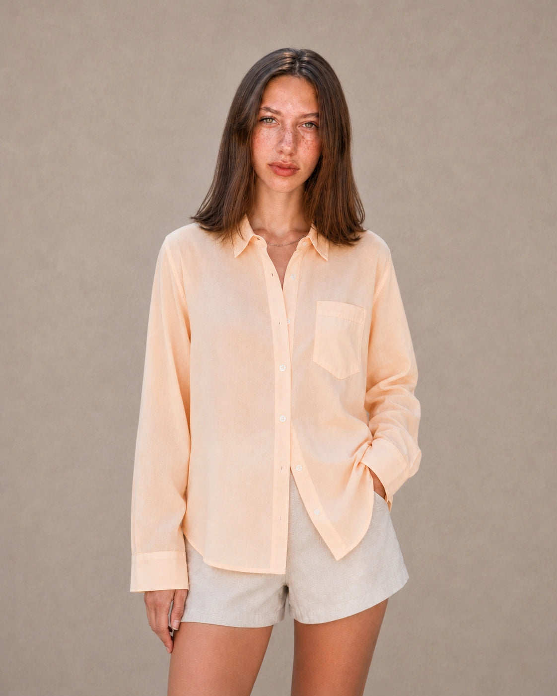 Vrouw draagt een oranje tencel-linnen doorknoopblouse met reverskraag, vooraanzicht.