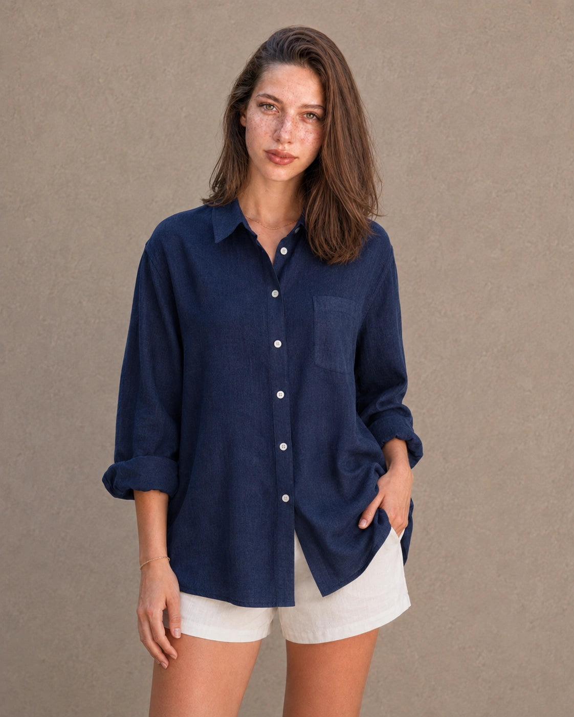 Volledige look van een vrouw in een lang marineblauw linnen-katoenen blousejasje, gecombineerd met een witte short.