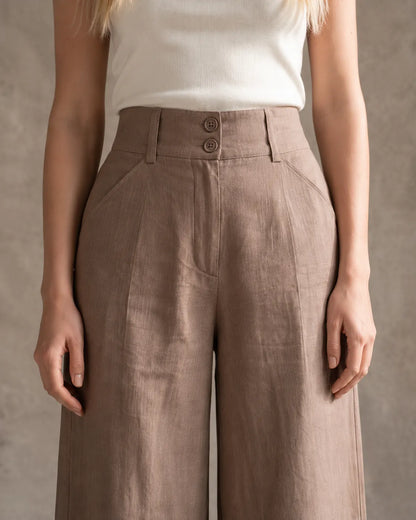 Close-up van de dubbele knoopsluiting en schuine zak van een wijde broek dames in Khaki katoen-linnenmix.