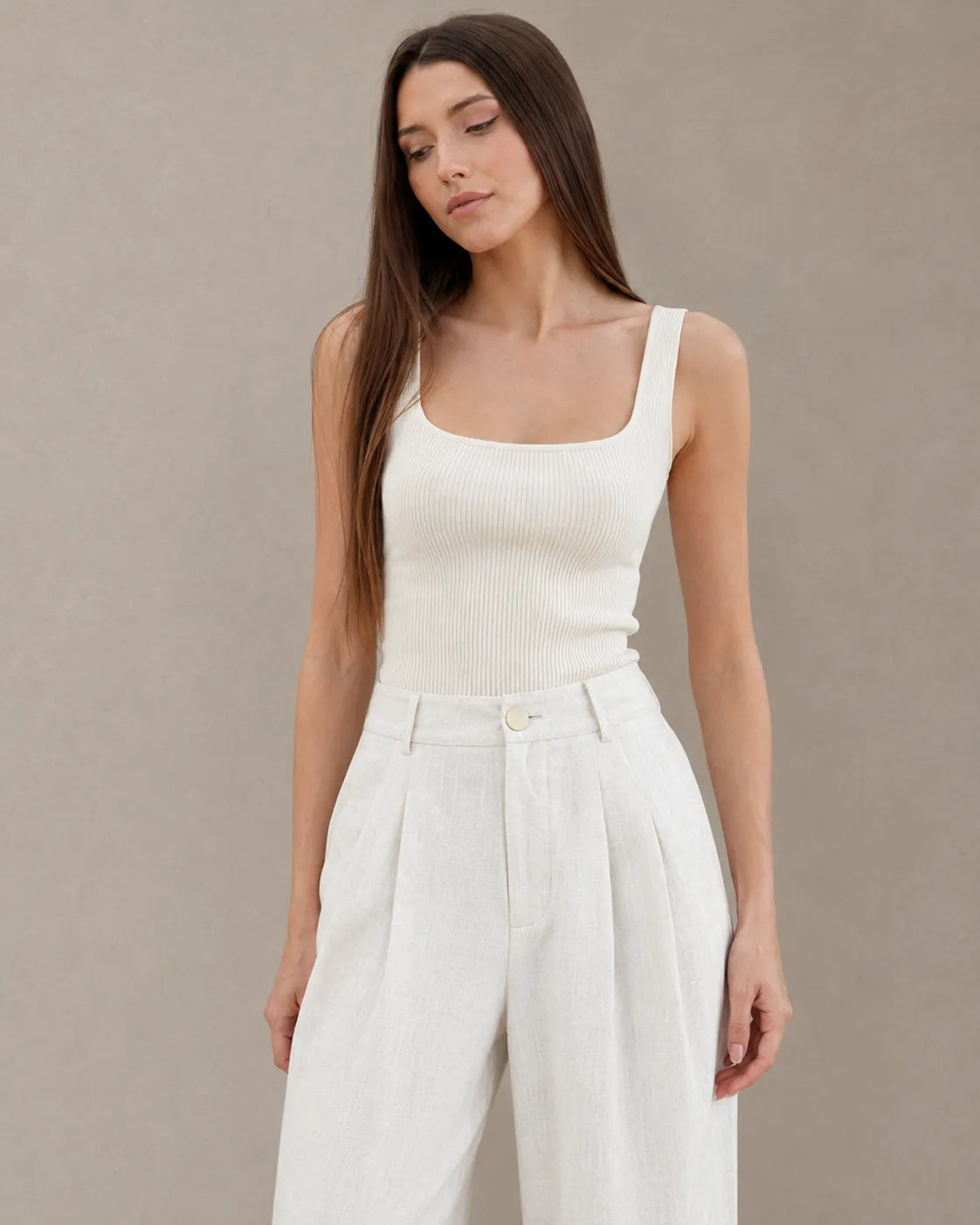 Close-up of the pleated high waistband on white wide-leg summer trousers in cotton-linen-polyester blend.