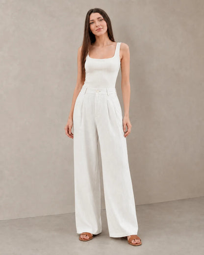 Close-up front view of model in white wide-leg summer trousers in a cotton-linen-polyester blend with a pleated high waist.