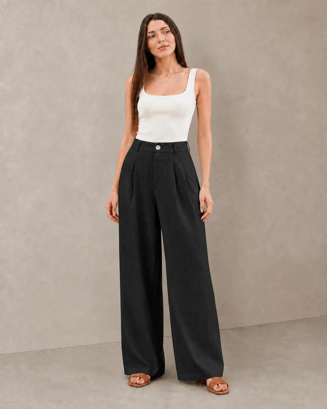 Close-up front view of model in black wide-leg summer trousers in a cotton-linen-polyester blend with a pleated high waist.