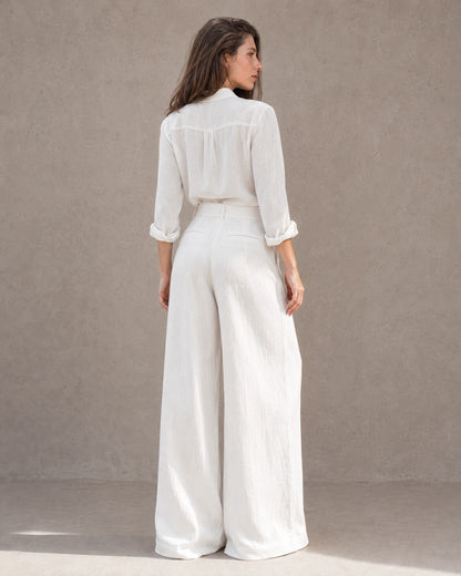 Achteraanzicht van model in een wijde broek dames in witte katoen-linnenmix met hoge taille en bijpassend linnen overhemd.
