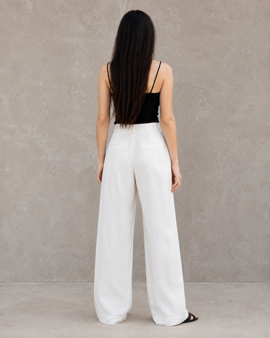 Achteraanzicht van model in een witte wijde broek dames in katoen-linnenmix met steekzakken.