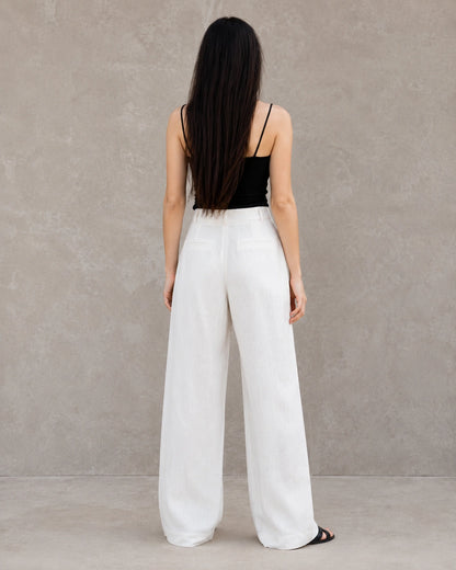Achteraanzicht van model in een witte wijde broek dames in katoen-linnenmix met steekzakken.