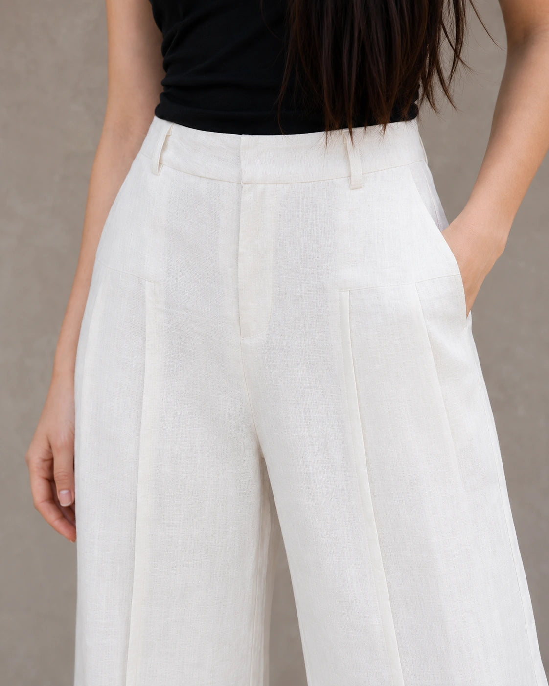 Close-up van de geplooide hoge taille en steekzak van een witte wijde broek dames in katoen-linnenmix.
