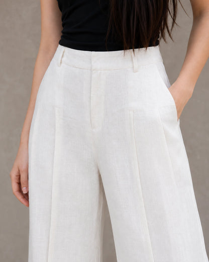 Close-up van de geplooide hoge taille en steekzak van een witte wijde broek dames in katoen-linnenmix.