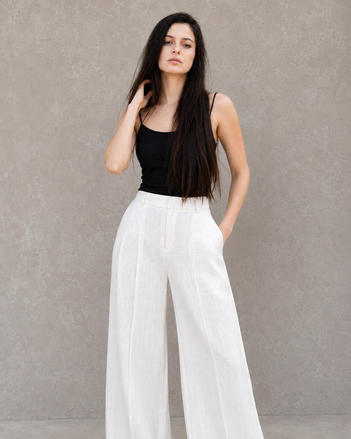 Close-up vooraanzicht van model in een witte wijde broek dames in katoen-linnenmix, hand rustend op de heup.