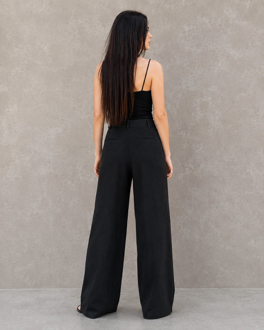 Achteraanzicht van model in een zwarte wijde broek dames in katoen-linnenmix met steekzakken.