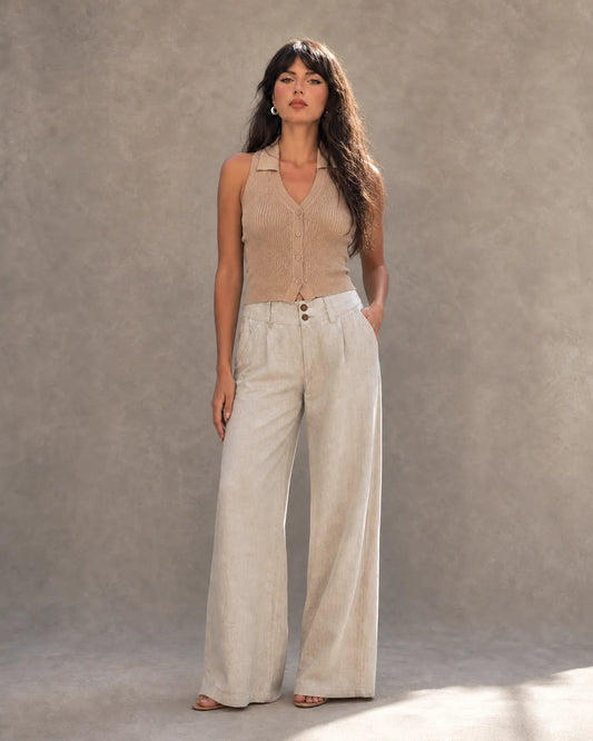 Model draagt een enkellange linnen broek dames in gebroken wit met dubbele knooptaille, gestyled met een taupe gebreid vestje, vooraanzicht.