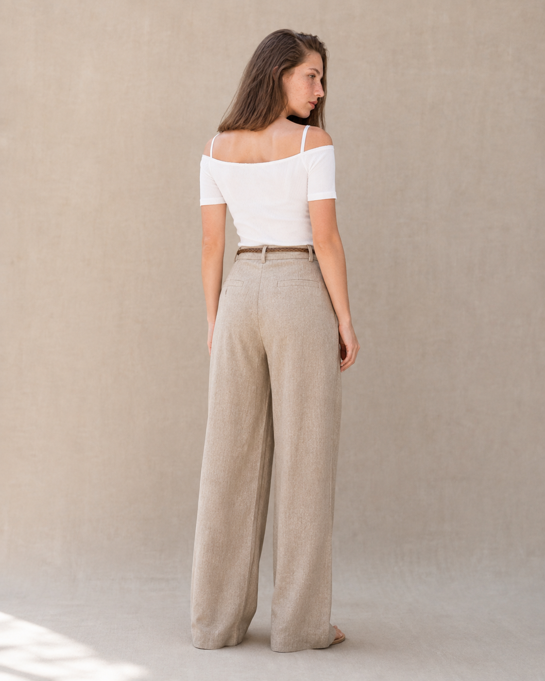 Achteraanzicht van model in een kaki linnen broek dames met rechte pijp, hoge taille en gevlochten riem.