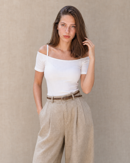 Model draagt een kaki linnen broek dames met rechte pijp en hoge taille, gestyled met een wit topje en gevlochten riem, vooraanzicht.