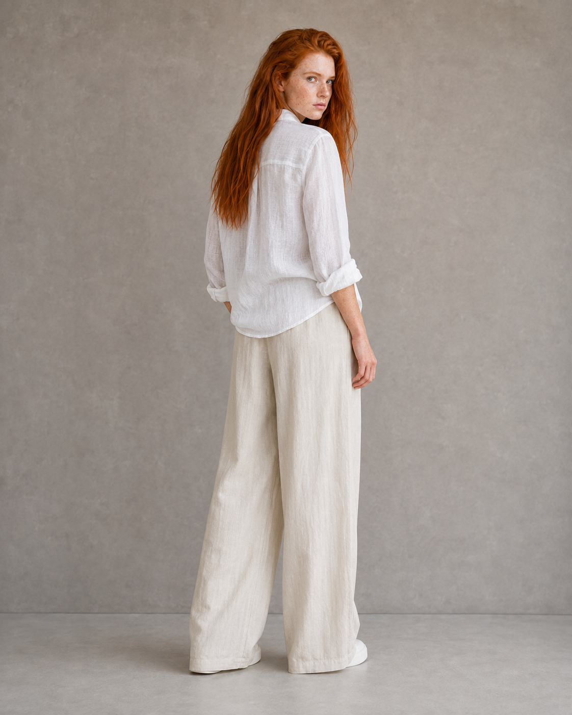 Back view of model wearing beige wide-leg linen-cotton trousers with an elasticated drawstring waist.