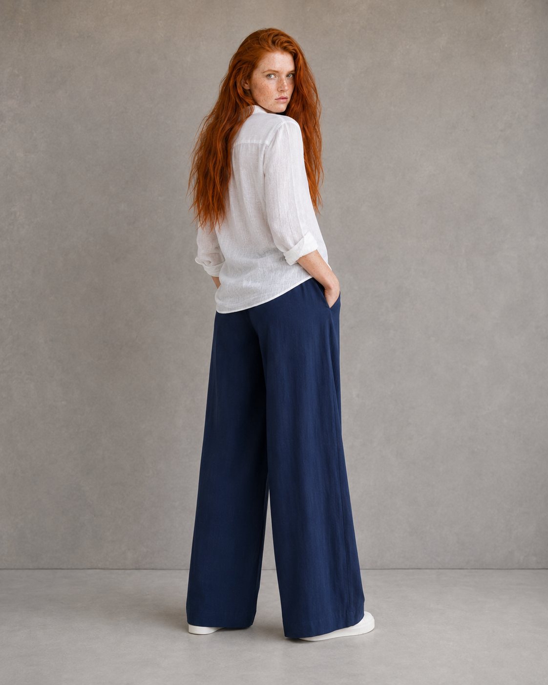 Back view of model wearing burgundy wide-leg linen-cotton trousers with an elasticated drawstring waist.