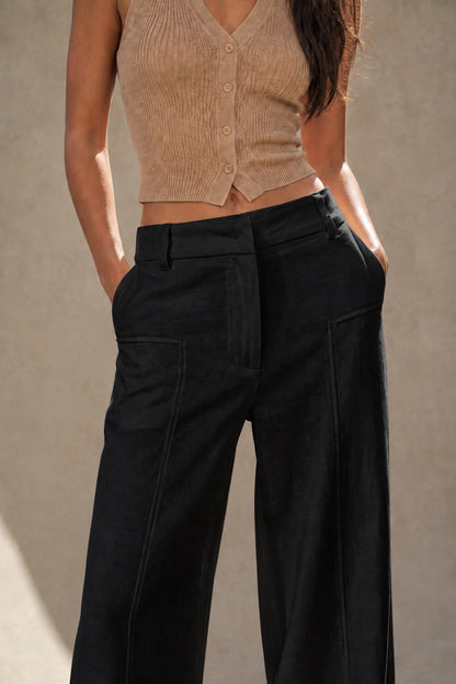 Close-up of the front waistband, belt loops and patch pockets on navy wide-leg linen-cotton trousers, styled with a cropped knit top.