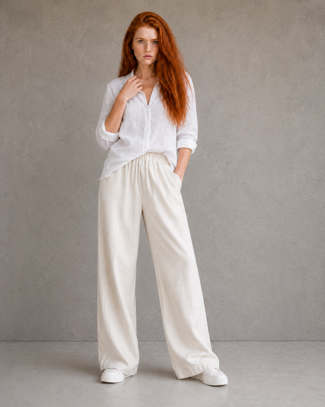 Model wearing orange wide-leg linen-cotton trousers, hand in pocket, front view.