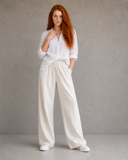 Model wearing orange wide-leg linen-cotton trousers, hand in pocket, front view.