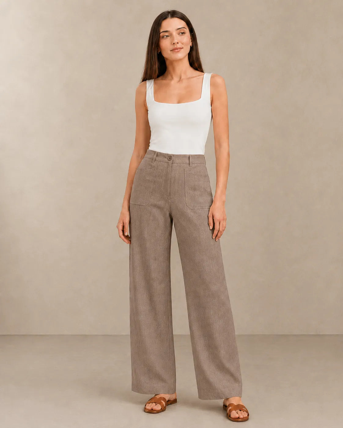 Model wearing latte-coloured linen wide-leg trousers with a high waist, styled with a white square-neck top, front view.