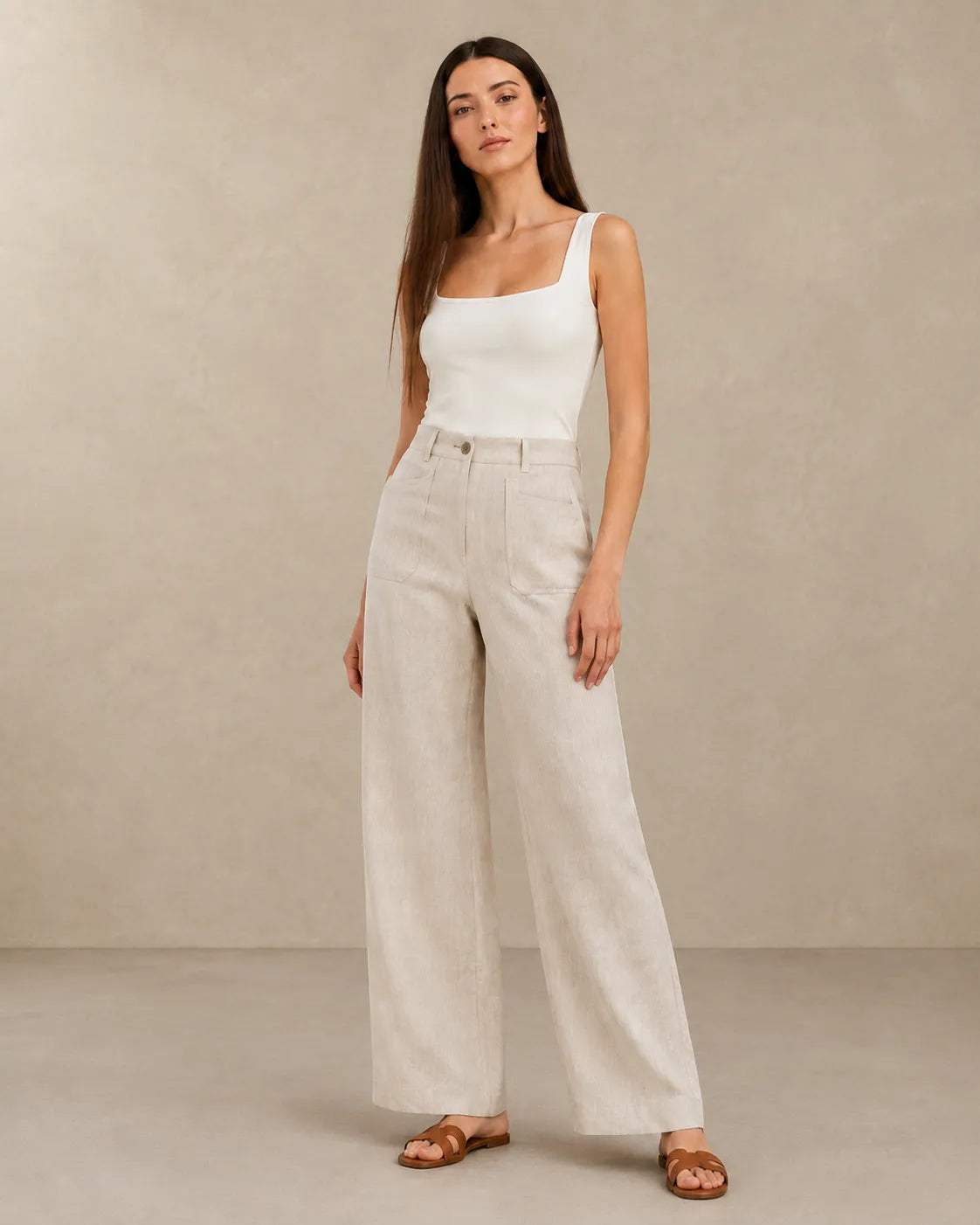 Model wearing natural linen wide-leg trousers with a high waist, styled with a white square-neck top, front view.