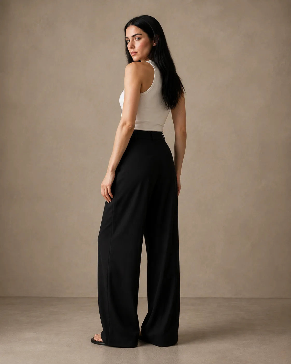 Three-quarter back view of model wearing black wide-leg trousers in linen-tencel-viscose blend.