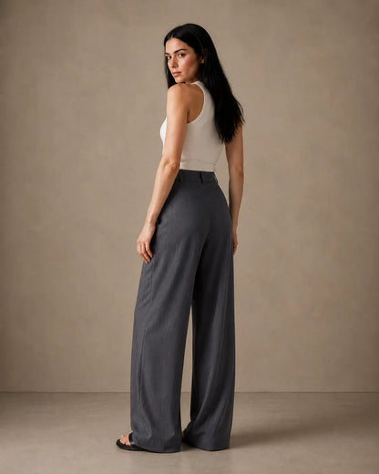 Three-quarter back view of model wearing dark grey wide-leg trousers in linen-tencel-viscose blend.