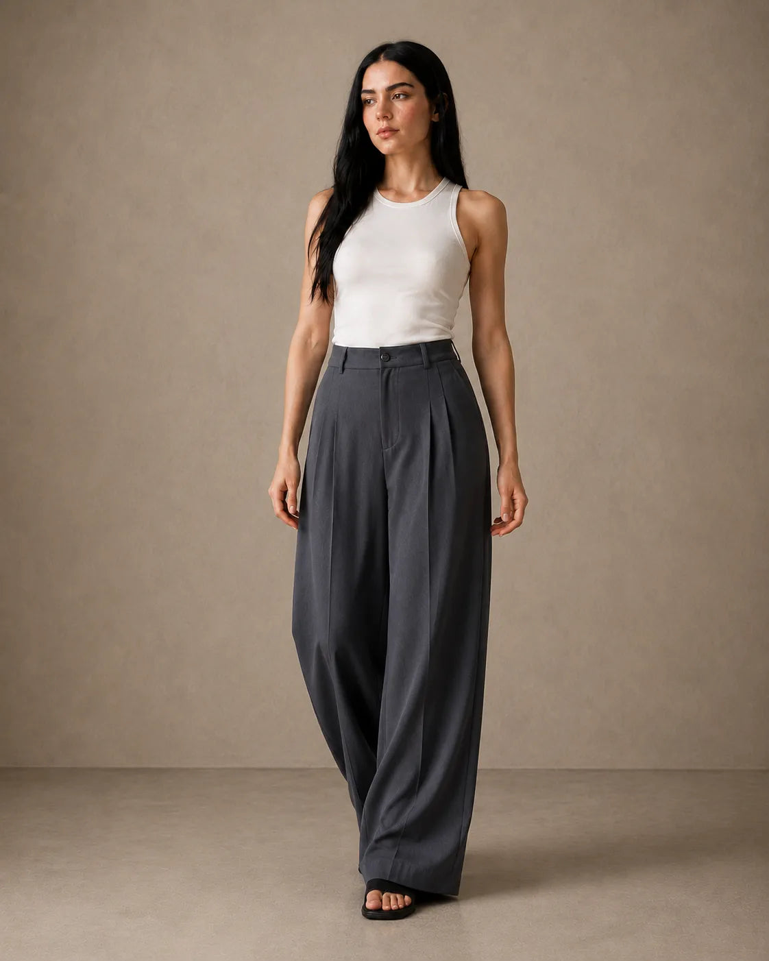 Close-up front view of model in dark grey wide-leg trousers in a linen-tencel-viscose blend with pleated waistband.
