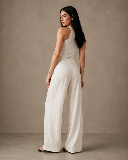 Three-quarter back view of model wearing oatmeal white wide-leg trousers in linen-tencel-viscose blend.