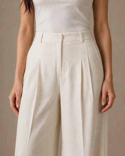Close-up of the pleated high waistband on oatmeal white wide-leg linen-tencel-viscose trousers.