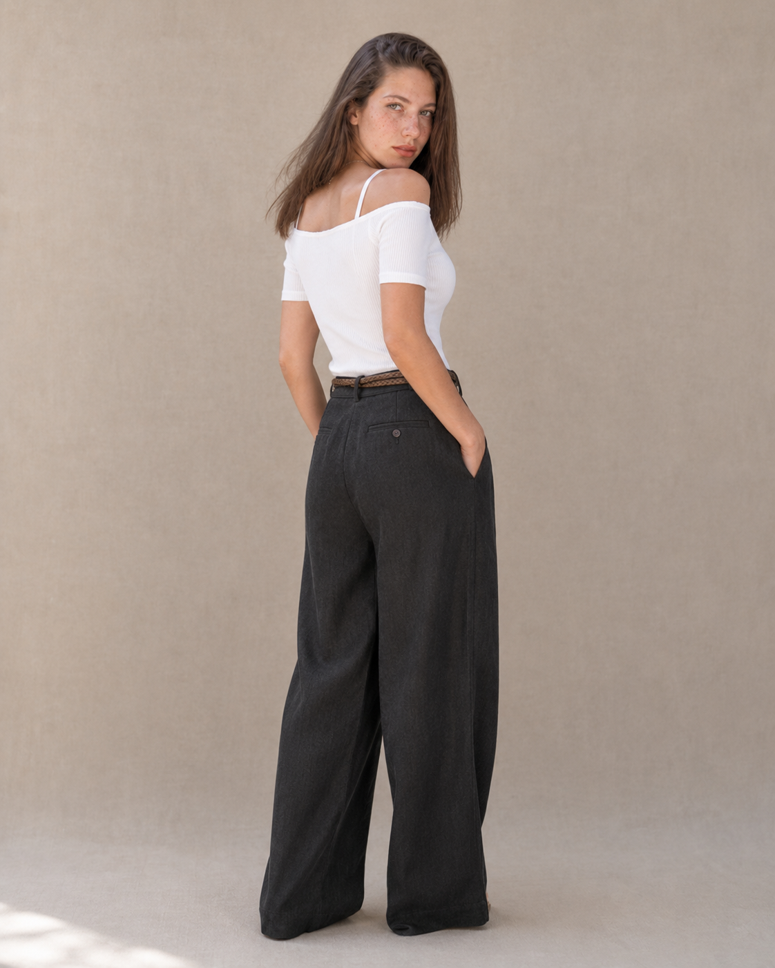 Achteraanzicht van model in een zwarte linnen broek dames met rechte pijp, hoge taille en gevlochten riem.