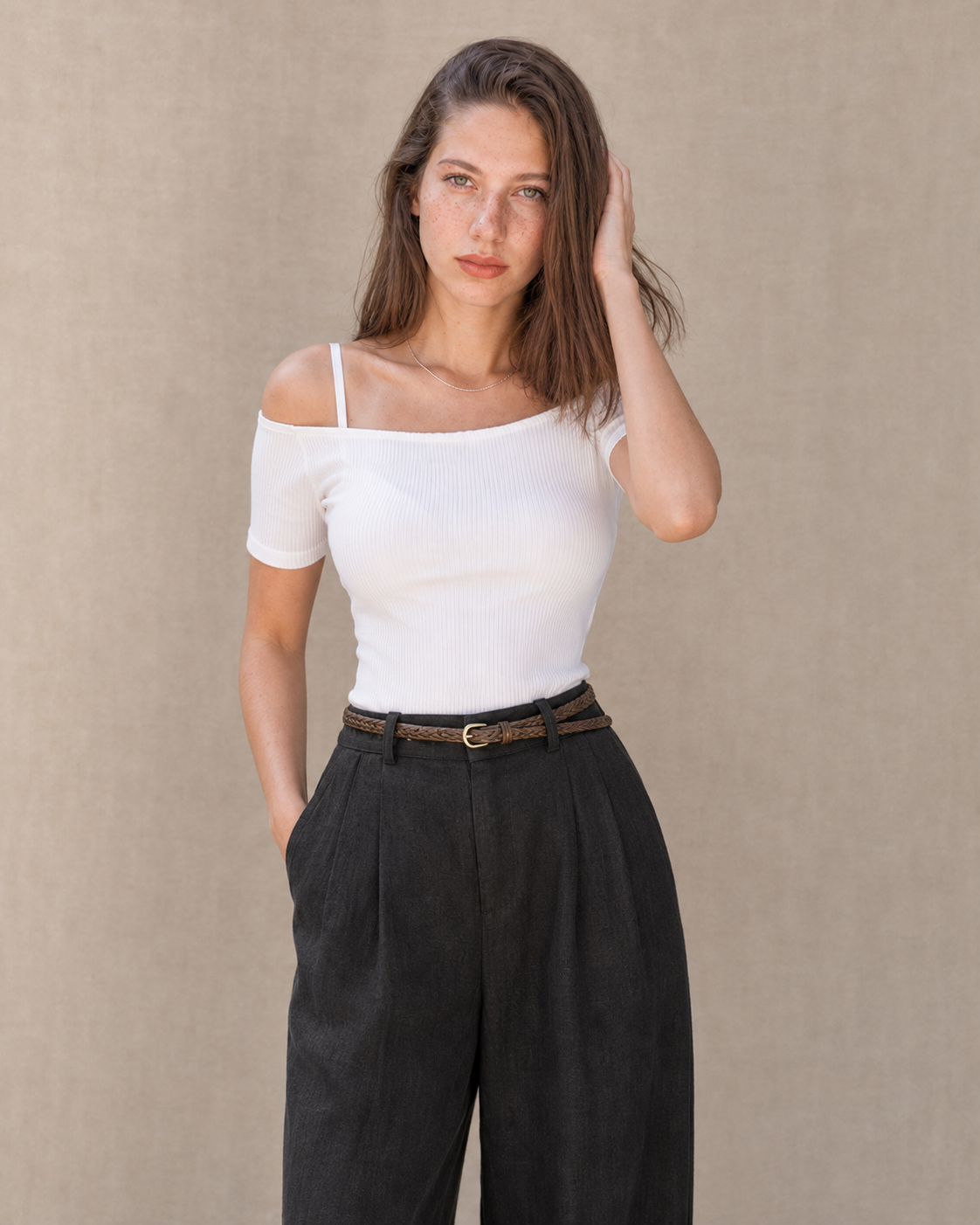Model in een zwarte linnen broek dames met rechte pijp en een hand in de zak, vooraanzicht, met zicht op de rechte lijn tot aan de zoom.