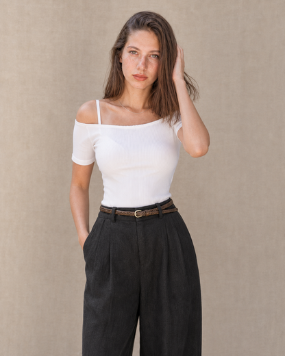 Model in een zwarte linnen broek dames met rechte pijp en een hand in de zak, vooraanzicht, met zicht op de rechte lijn tot aan de zoom.